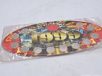 Photo of 12 Canadian quarters from 1999 mounted on a colorful card with the year 1999 and Canadian maple leaf, all sealed in plastic.