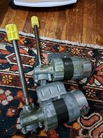 Two vintage Gearmaster electric motors with threaded shafts and yellow plastic covers, placed on a decorative rug, showing overall condition and appearance.