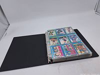Binder open showing nine vintage hockey cards with multicolor borders in plastic sleeves