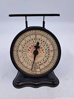 Front view showing circular dial with markings 'PRECISION POSTAL SCALE' and pointers.