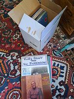 Cardboard box filled with vinyl LP records on patterned rug