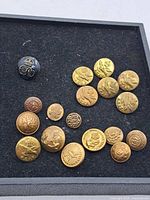 Lot of assorted vintage military buttons including several brass R.C.A.F. eagle insignia buttons scattered on a black felt surface.