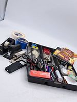 Overview photo of assorted vintage office supplies including staplers, tape dispensers, scissors, pens, glue sticks, and handmade notebooks on a white background.