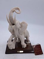 Elephant resin sculpture with raised trunk on wooden stand