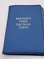 Blue folder cover with gold text 'Britain's First Decimal Coins'