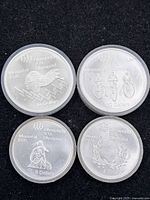 Four silver Montreal 1976 Olympic coins in protective capsules on black background