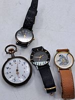 Four watches visible: one pocket watch and three wristwatches with varying dials and bands.