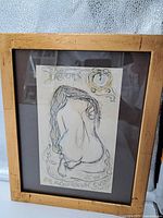 Full view of framed drawing showing nude figure on a cushion.
