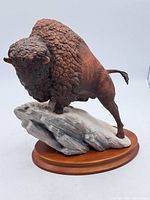 Front view of the bisque porcelain bison sculpture showing the detailed fur texture and sculpted rock base.