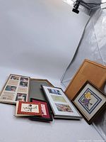 Multiple vintage frames and cross stitch artworks arranged on a white surface.