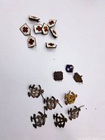 Multiple small pins arranged in two groups, mostly military insignia and Red Cross enamel pins on white background