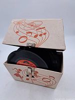 Box with multiple 45rpm vinyl records inside, partially open showing the records