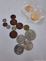 Photo showing multiple assorted coins including silver-toned, copper, and coins with holes, some sealed in plastic.