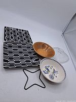 Photo showing two rectangular plates with black and white geometric patterns, a wooden bowl, a ceramic bowl, and a clear lid for wooden bowl.