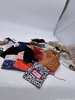 Photo showing an assortment of fabric jewellery bags in different colors and styles laid out flat, including drawstring pouches and snap button bags with embroidery.