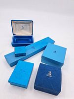 Six Birks branded boxes and cases displayed, showing different sizes, colors ranging from light to dark blue, and textures including suede and cardboard.