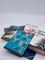 Five hardcover books stacked showing titles by Helen Simpson and Art Pepper.