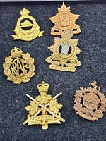 Top view displaying all six Canadian military badges arranged on black foam. Various symbols and crowns visible with signs of use and age.