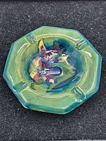 Top view of the octagonal glazed ceramic ashtray with colorful floral decoration in center.