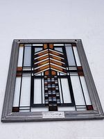 Full view of stained glass panel showing geometric design with amber and clear glass in a grey frame.
