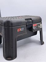 Side view showing the sturdy black plastic construction with slightly worn sticker and structural legs.