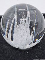 Front view of the clear glass paperweight showing vertical air bubble inclusions inside.