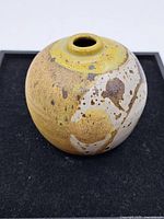 Image showing round ceramic vase with a narrow top opening, glazed in yellow, brown, and off-white speckles with textured surface