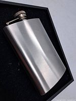 Front view of curved stainless steel 8oz flask showing brushed finish and screw cap.
