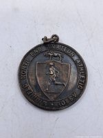 Front view of the round sterling silver sports medal with embossed athlete, dog, and association inscription.