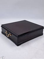 Closed view of vintage square tea chest with brass handle and dark wood finish.