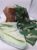Three silk scarves arranged together showing colors and designs: green Jacamar with carriage prints, light green Anuette Paris with blue border, and multicolored vintage patterned scarf.