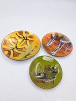 Overview of three enamel dishes showing varied abstract designs and colors