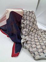 Two vintage silk scarves displayed, one draped showing floral pattern, the other geometric pattern with navy blue and red edges.
