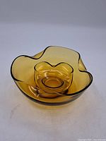 Photo of large amber glass bowl showing wavy rim and rounded base, translucent amber glass.