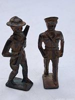 Front view of two WWI-era metal toy soldiers showing detailed uniforms and headwear