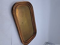 Top view of vintage brass tray in oak frame, showing overall shape and wear.