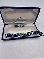 Blue velvet box interior labeled La Reine containing bracelet and earrings