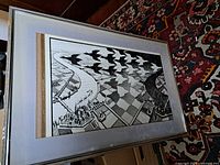 Framed black and white print after M.C. Escher with tessellated birds and geometric patterns, photo angled showing the frame and print details.