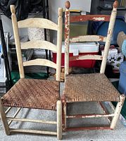 Front view showing two antique wooden ladder back chairs with woven seats, one cream colored and one red with cream, both with chipped paint and signs of wear.