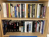 Wide bookshelf image showing two rows of various books including fiction and Twilight series with titles like 'Breaking Dawn', and others on government, society, and politics.