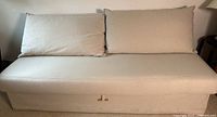 Front view of beige IKEA sofa bed with cushions.