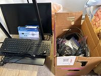 Dell monitor with two black USB keyboards and boxed Trendnet KVM switch cables in a box next to the monitor.