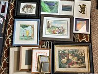 Various framed and unframed prints laid out on carpet. Prints include watercolor dragonfly, Russian cub, Pooh prints, zebra, still life with fruit and flowers. Several empty frames included.