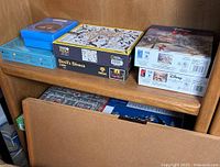 Shelf with multiple jigsaw puzzle boxes, including 'Devil's Dinner' and Disney puzzles.