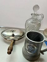 Photo showing the silverplate handled serving dish with lid, pewter US Senate mug, and glass decanter with stopper.