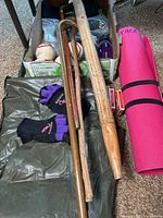 Overview of lot including walking stick, cane, rain stick, volleyballs, gloves, inflatable mattress, and water bottles