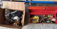 Box containing 2 heavy duty staplers, staples, electrical supplies including tape measure and a small black pouch