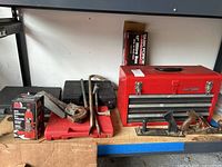 Craftsman red 3-drawer tool chest with assorted hand tools and boxed tools on a workbench