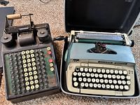 Photo showing the Burroughs adding machine alongside the Smith-Corona typewriter in its case.
