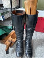 Front view of two black leather vintage riding boots with wooden keepers inside to maintain shape. Boots show signs of use with creasing and scuffs.